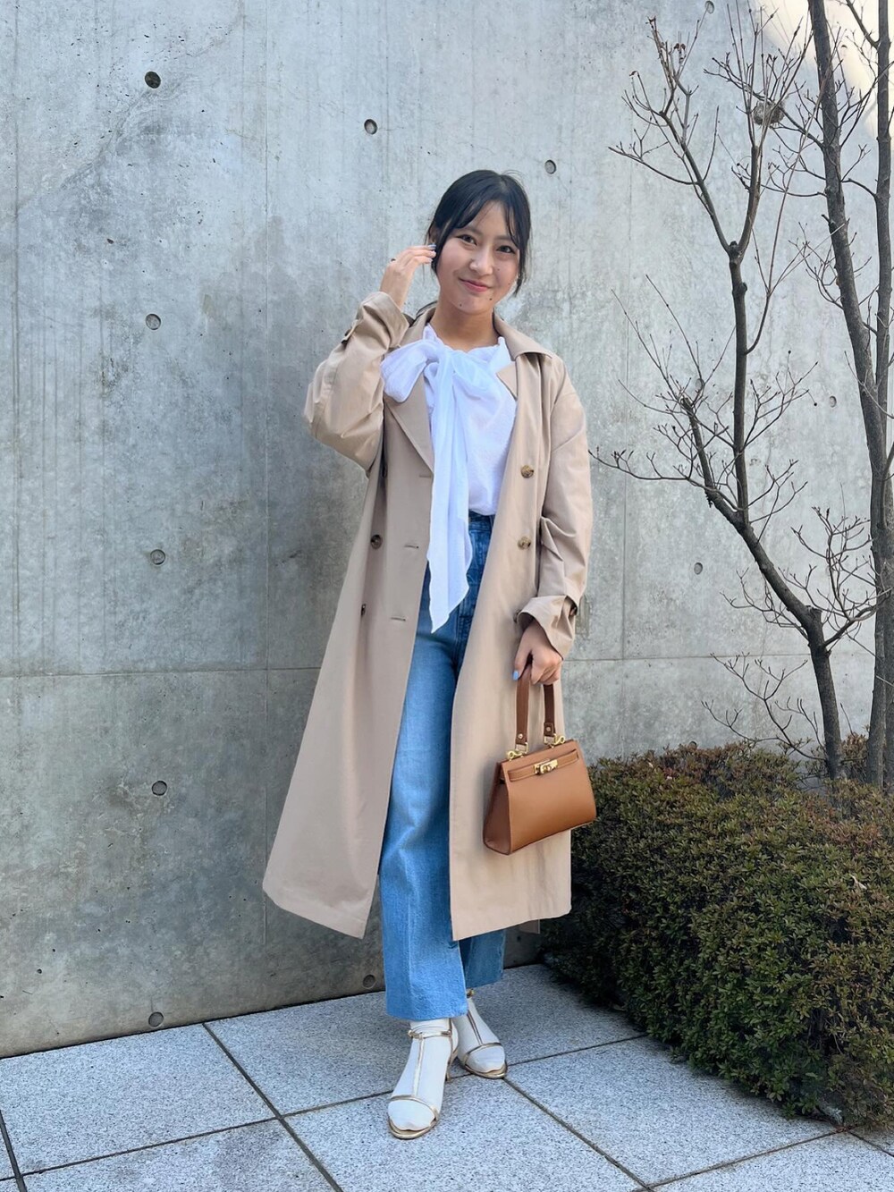 ホワイト系のシャツ/ブラウス、ベージュ系のトレンチコート、ブルー系のデニムパンツを着用したレディースの春コーディネートの3枚目の写真