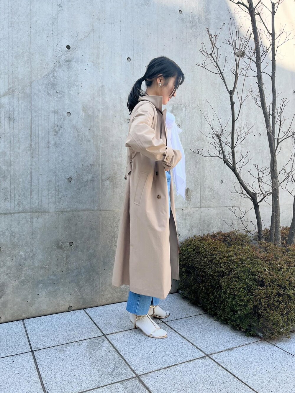 ホワイト系のシャツ/ブラウス、ベージュ系のトレンチコート、ブルー系のデニムパンツを着用したレディースの春コーディネートの4枚目の写真