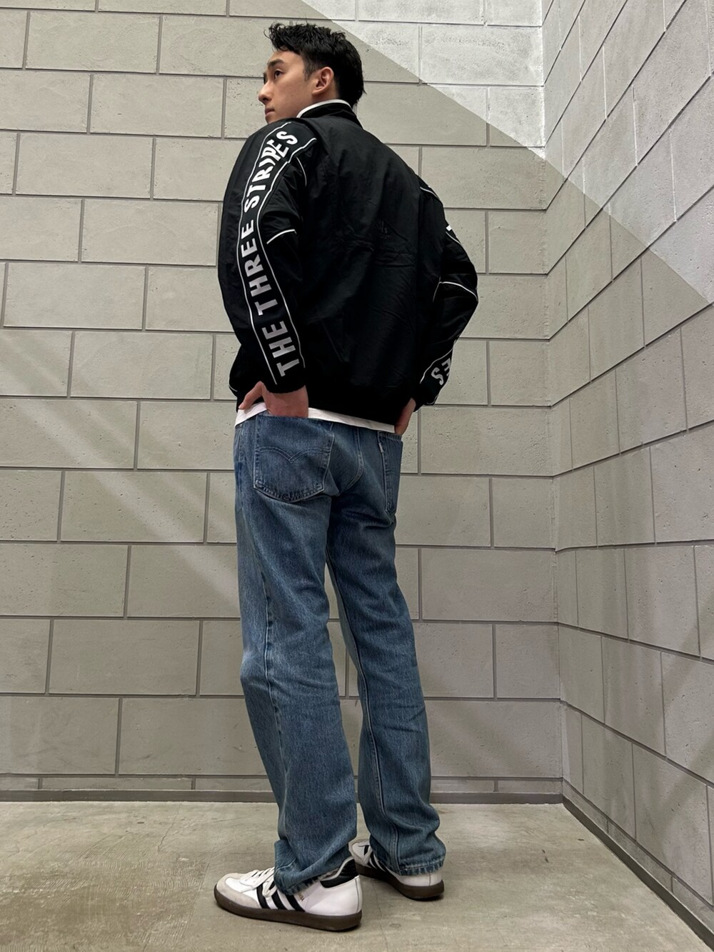 ブラック系のナイロンジャケット、ホワイト系のスニーカーを着用したメンズの秋コーディネートの2枚目の写真