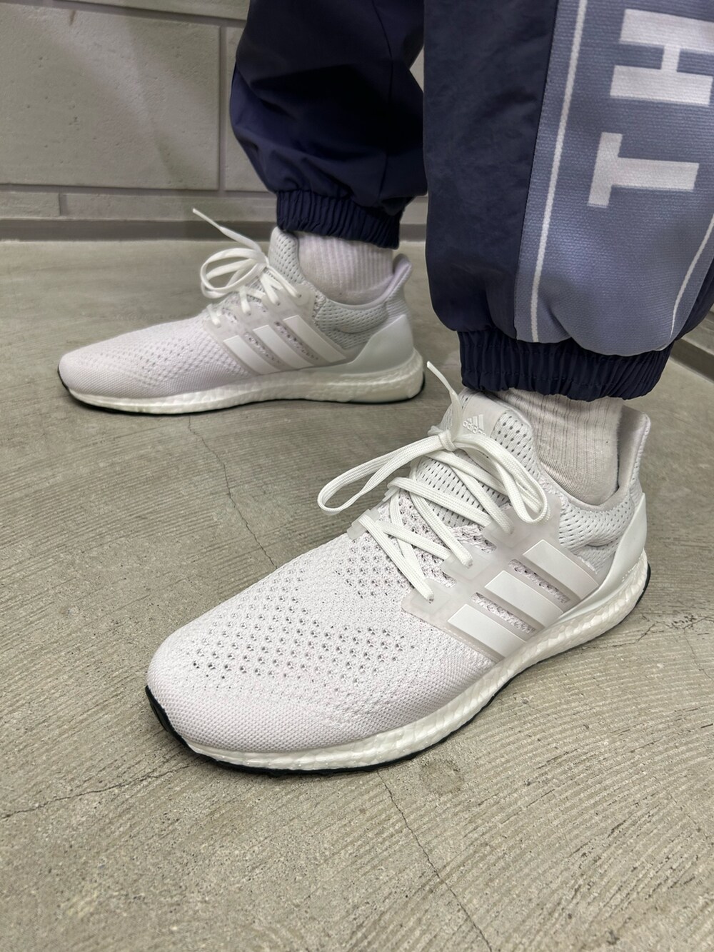 ホワイト系のスニーカー、ブルー系のパンツ、パープル系のトップスを着用したメンズの秋コーディネートの3枚目の写真