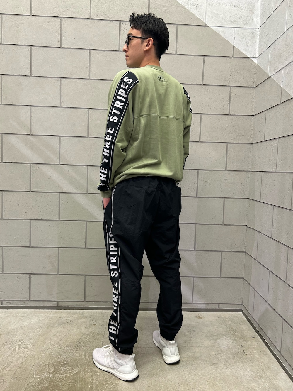 グリーン系のスウェット、ブラック系のその他パンツ、ホワイト系のスニーカーを着用したメンズの秋コーディネートの2枚目の写真