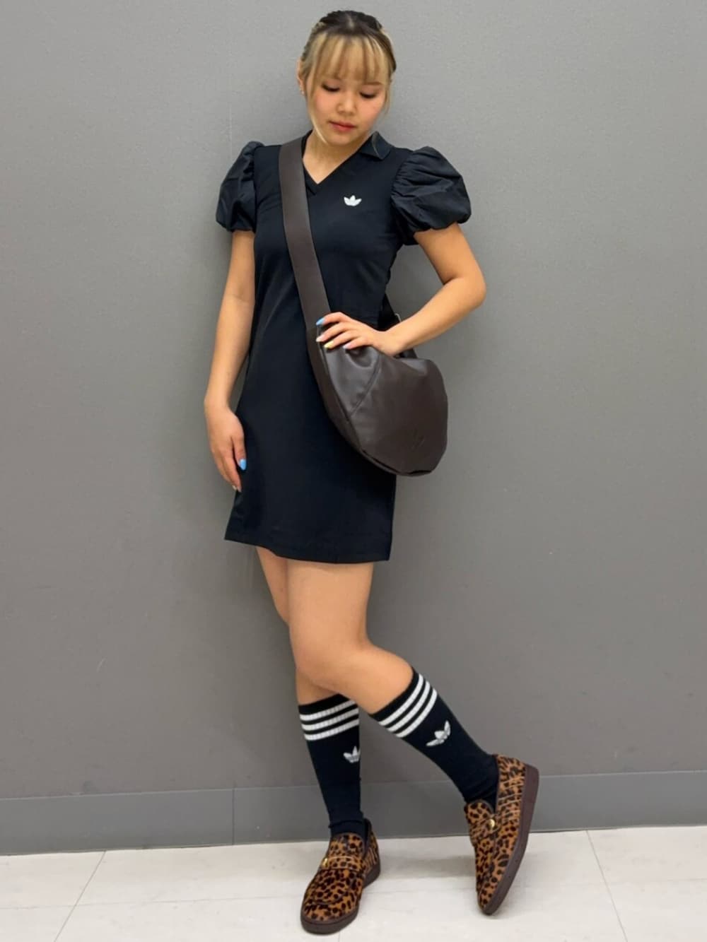 ブラウン系のショルダーバッグ、ブラック系のワンピース、ベージュ系のスニーカーを着用したレディースの春コーディネートの2枚目の写真