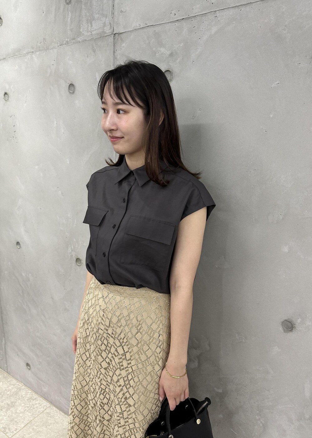 ブラック系のハンドバッグ、ブラック系のサンダル、ブラウン系のシャツ/ブラウスを着用したレディースの夏コーディネートの4枚目の写真