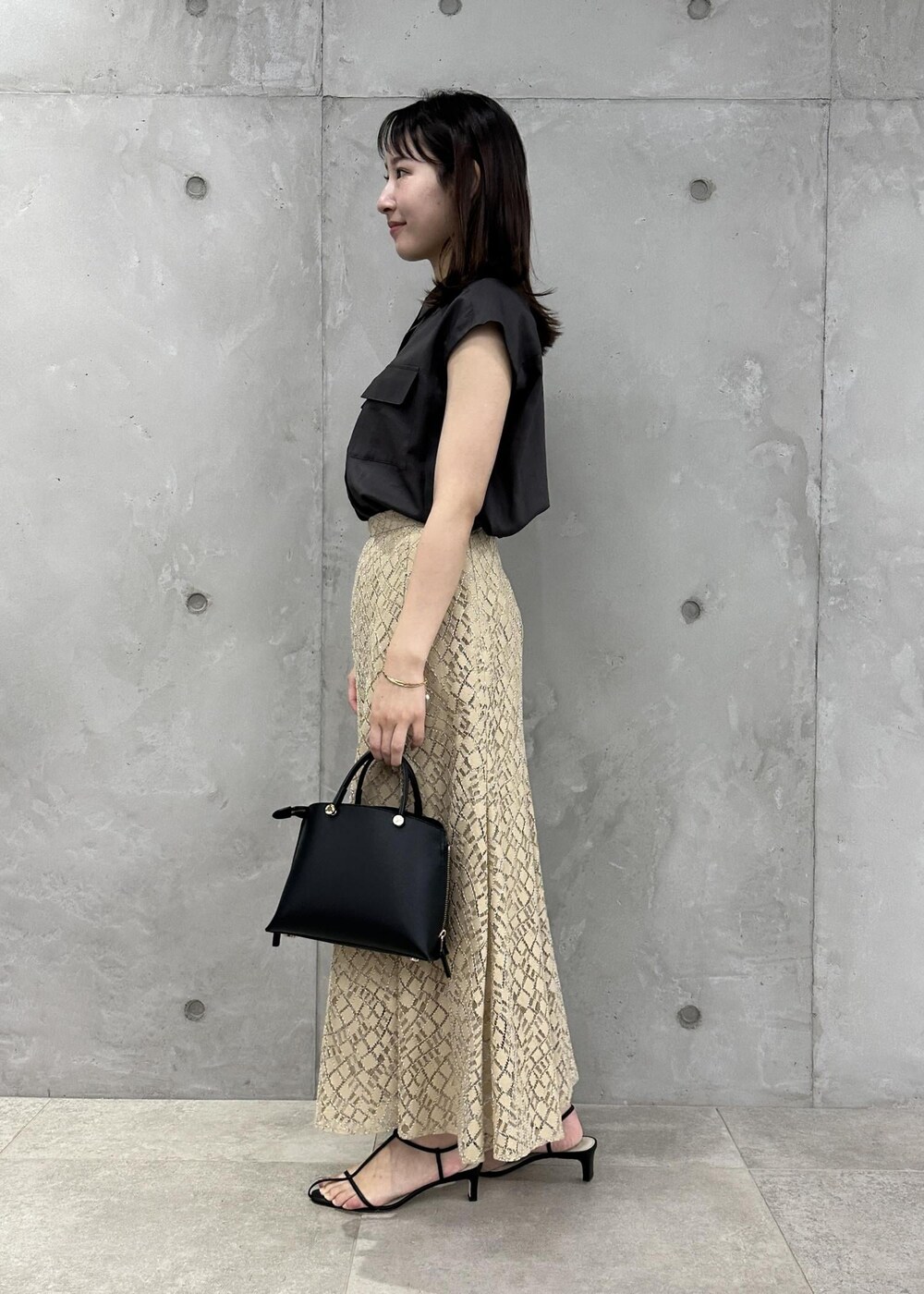ブラック系のハンドバッグ、ブラック系のサンダル、ブラウン系のシャツ/ブラウスを着用したレディースの夏コーディネートの2枚目の写真