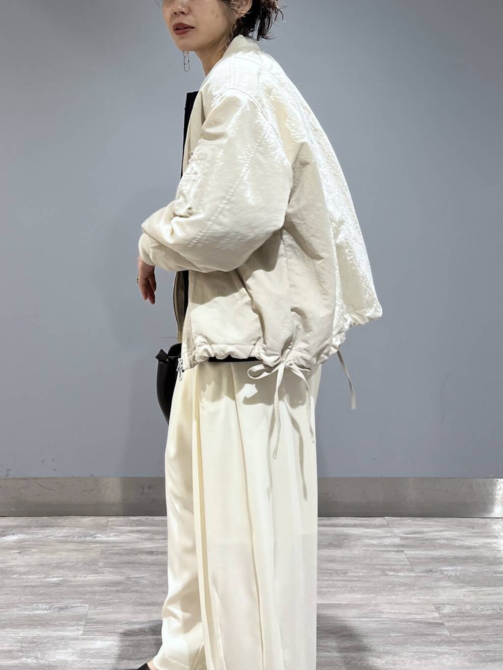 ホワイト系のスラックス、ベージュ系のMA-1、ブラック系のパンプスを着用したレディースの冬コーディネートの5枚目の写真