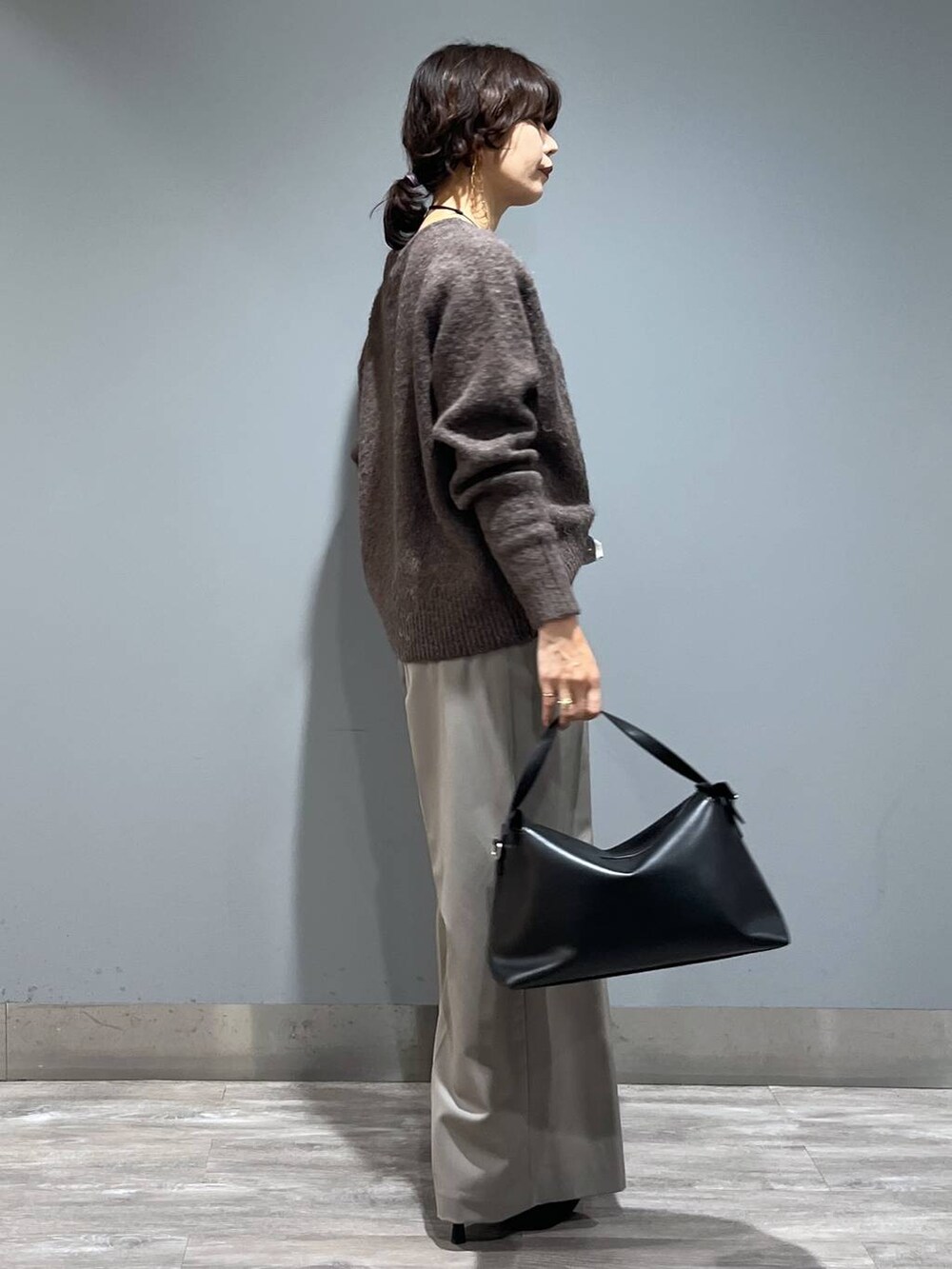 ブラウン系のニット/セーター、ブラック系のショルダーバッグ、ブラック系のブーツを着用したレディースの秋コーディネートの2枚目の写真