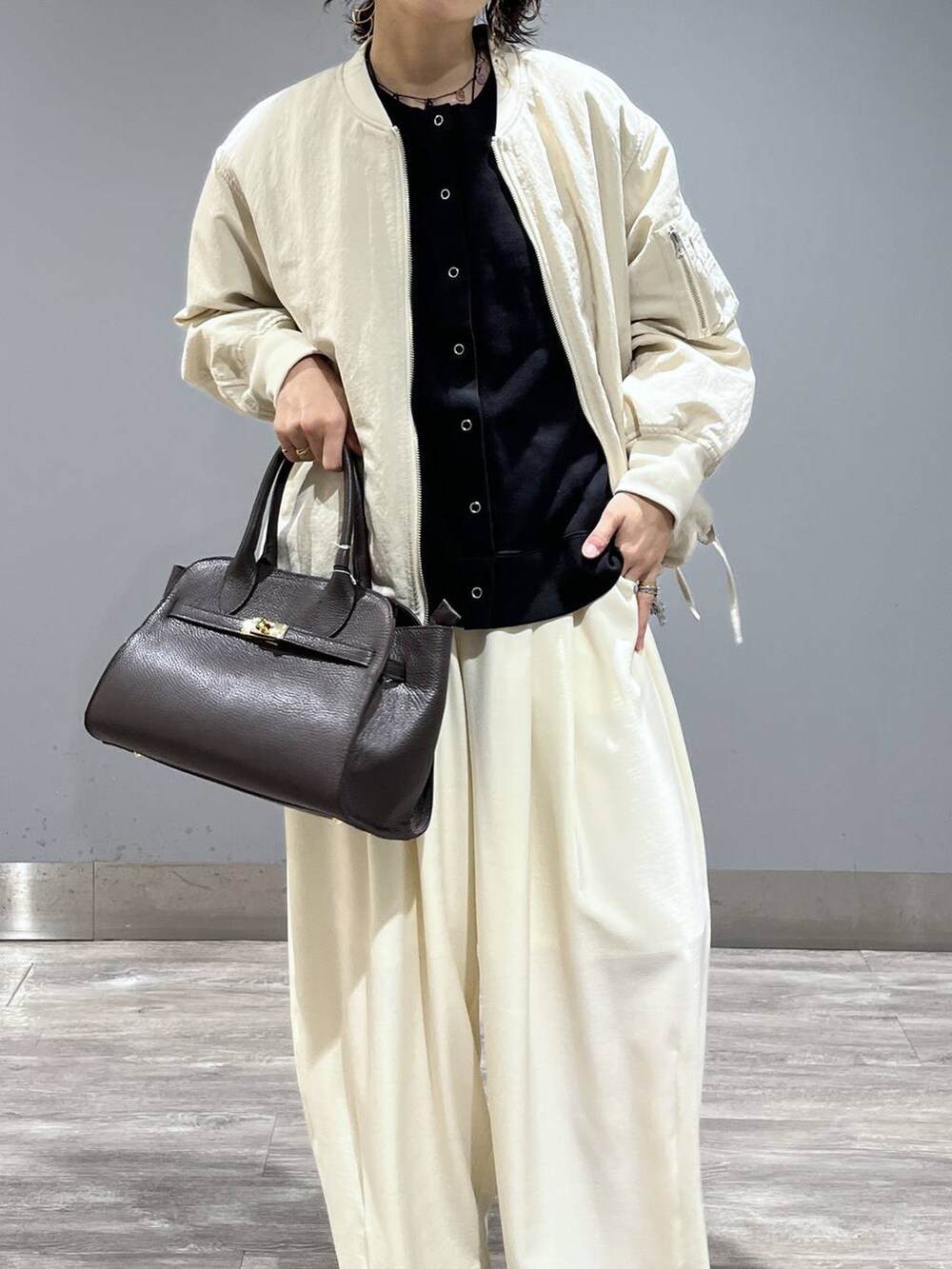 ホワイト系のスラックス、ベージュ系のMA-1、ブラック系のパンプスを着用したレディースの冬コーディネートの6枚目の写真