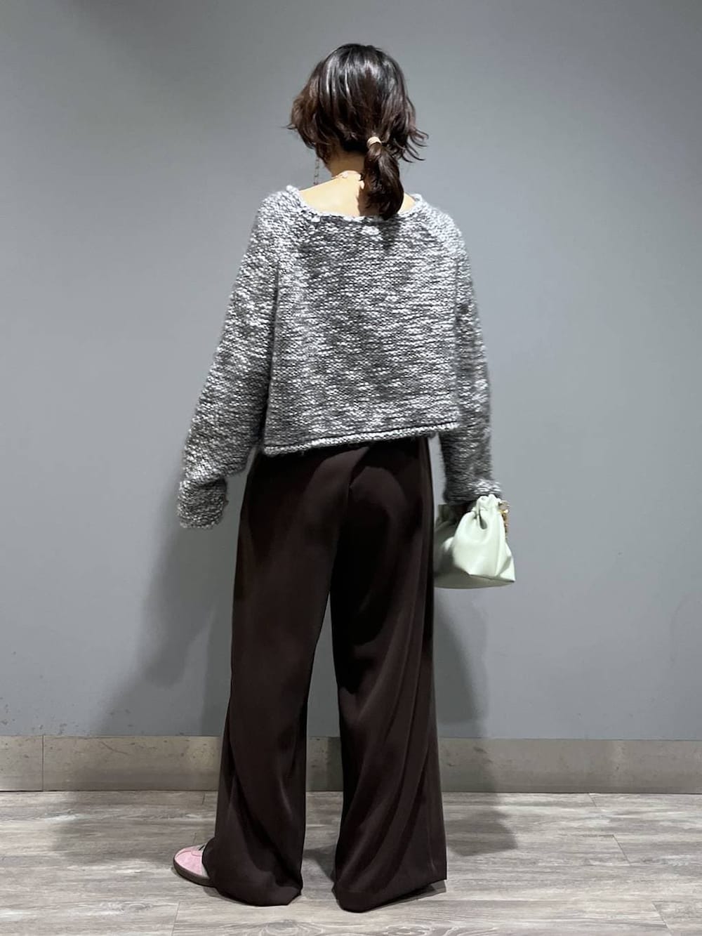 ブラウン系のスラックス、グリーン系のショルダーバッグ、グレー系のニット/セーターを着用したレディースの冬コーディネートの3枚目の写真