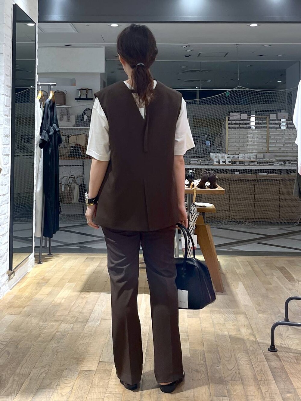 ブラック系のボストンバッグ、ホワイト系のTシャツ/カットソー、ブラウン系のパンツドレスを着用したレディースの秋コーディネートの3枚目の写真