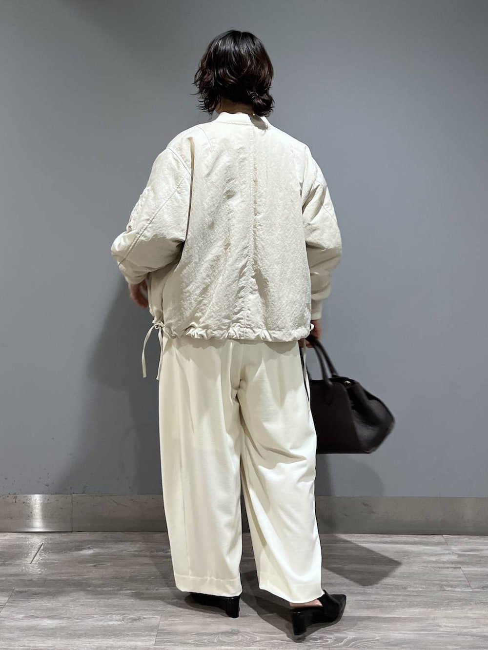 ホワイト系のスラックス、ベージュ系のMA-1、ブラック系のパンプスを着用したレディースの冬コーディネートの3枚目の写真