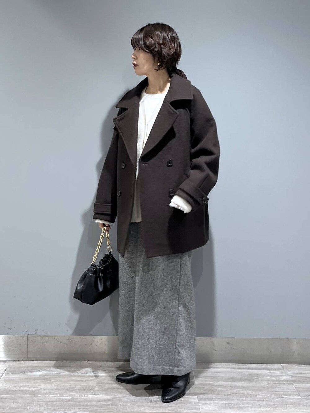 ブラウン系のピーコート、ホワイト系のカーディガン/ボレロ、ブラック系のブーツを着用したレディースの秋コーディネートの5枚目の写真