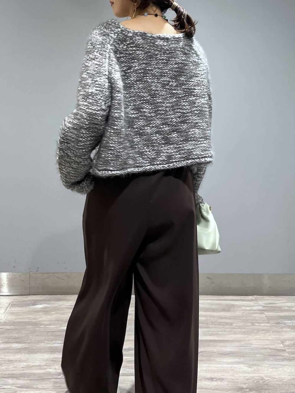 ブラウン系のスラックス、グリーン系のショルダーバッグ、グレー系のニット/セーターを着用したレディースの冬コーディネートの6枚目の写真