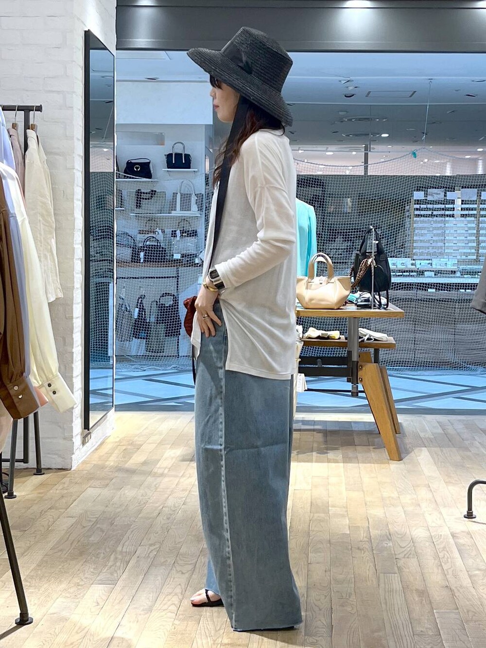 ブルー系のデニムパンツ、ブラック系のサンダル、ホワイト系のTシャツ/カットソーを着用したレディースの春コーディネートの3枚目の写真