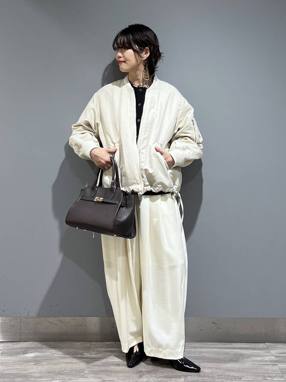 ホワイト系のスラックス、ベージュ系のMA-1、ブラック系のパンプスを着用したレディースの冬コーディネートの9枚目の写真