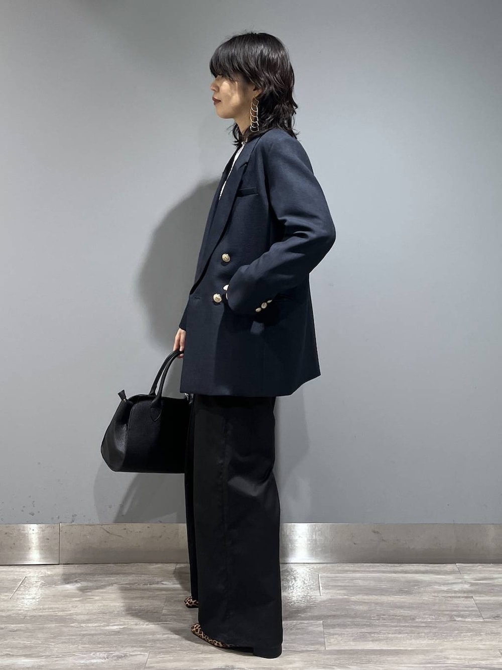 ブルー系のテーラードジャケット、ブラック系のショルダーバッグ、グレー系のニット/セーターを着用したレディースの春コーディネートの4枚目の写真