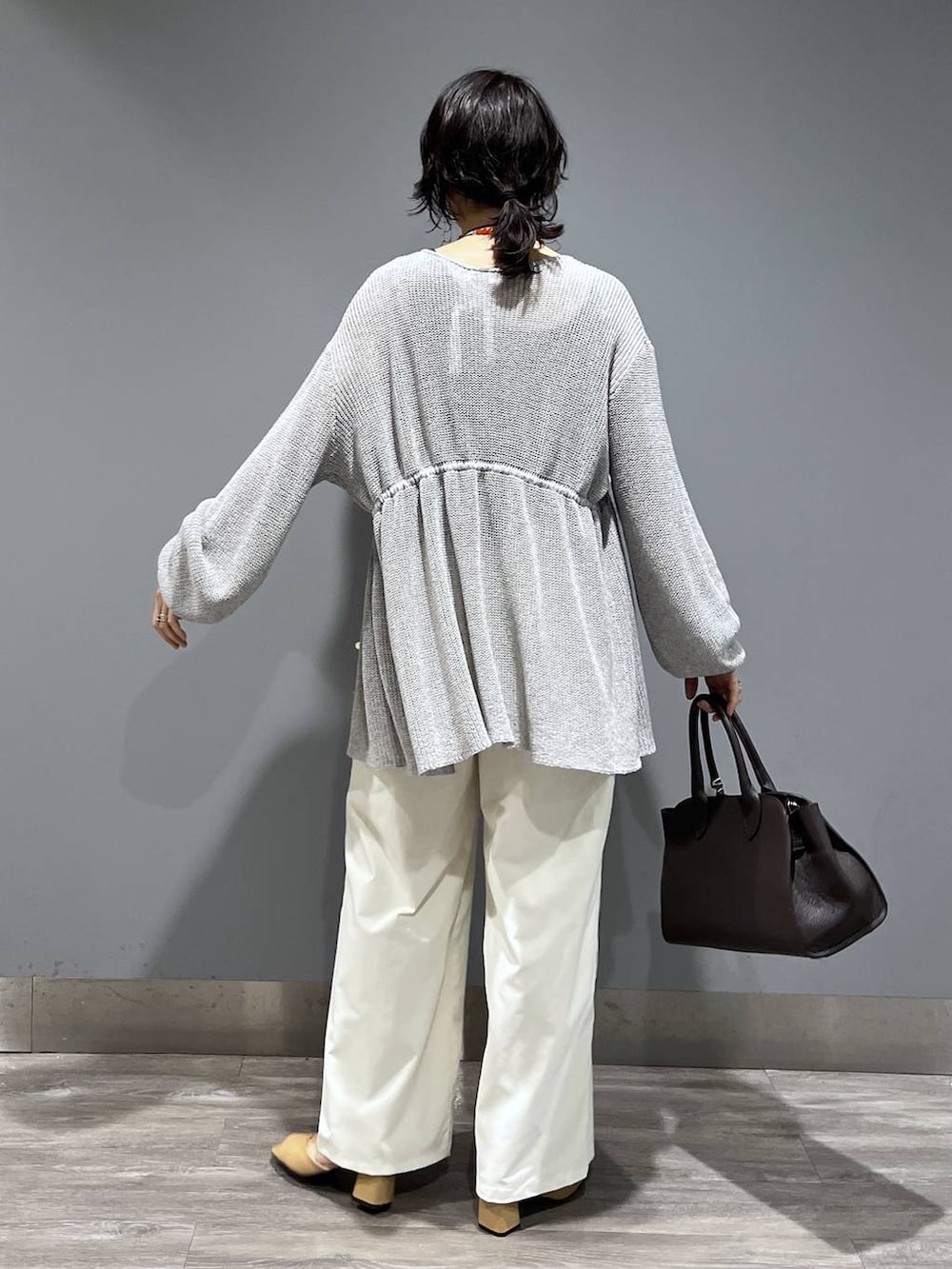 ブラウン系のショルダーバッグ、ホワイト系のスラックス、グレー系のカーディガン/ボレロを着用したレディースの春コーディネートの3枚目の写真