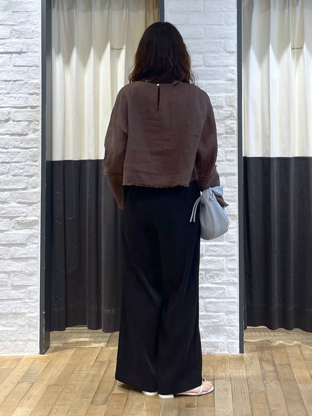 ブルー系のハンドバッグ、ブラウン系のシャツ/ブラウス、ホワイト系のサンダルを着用したレディースの秋コーディネートの3枚目の写真