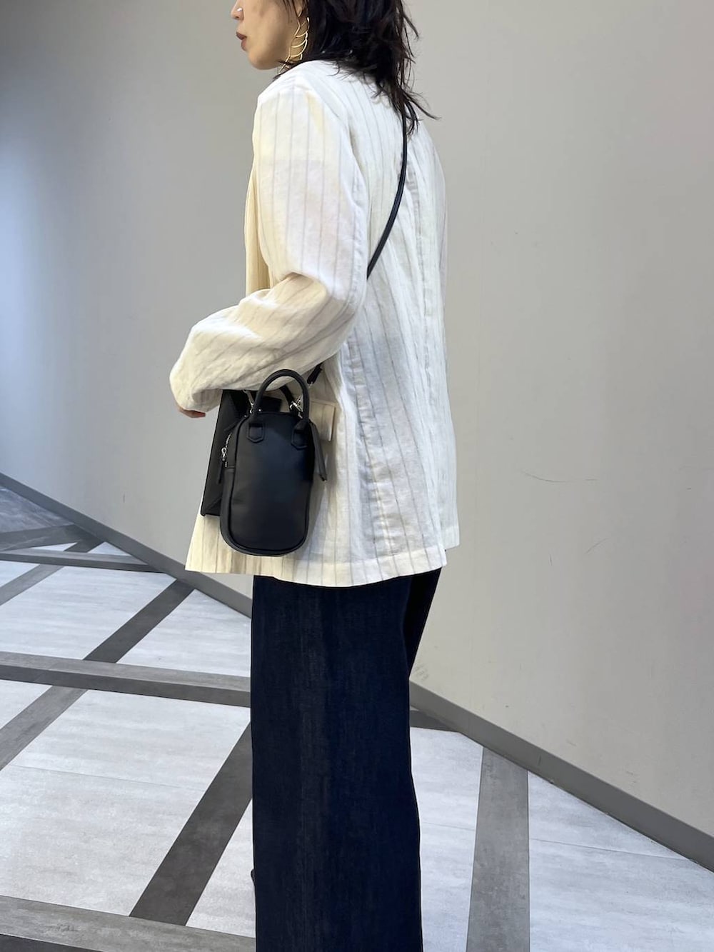 ベージュ系のテーラードジャケット、ブルー系のデニムパンツ、ブラック系のサンダルを着用したレディースの夏コーディネートの3枚目の写真