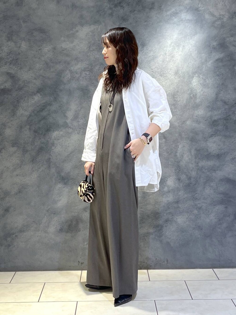 ブラック系のパンプス、ホワイト系のシャツ/ブラウス、グレー系のつなぎ/オールインワンを着用したレディースの春コーディネートの5枚目の写真