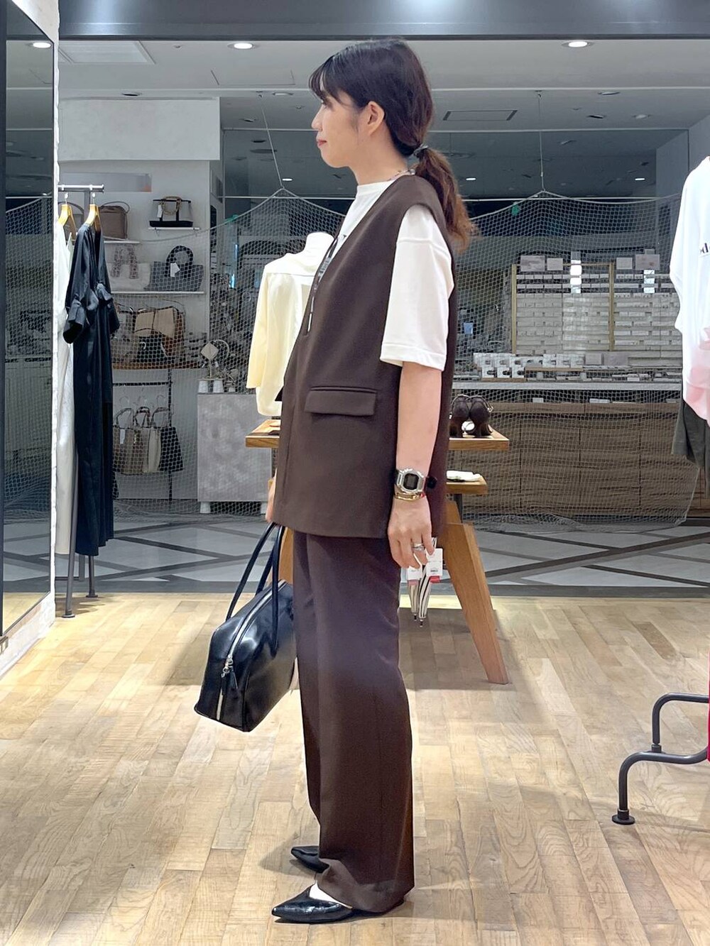 ブラック系のボストンバッグ、ホワイト系のTシャツ/カットソー、ブラウン系のパンツドレスを着用したレディースの秋コーディネートの5枚目の写真