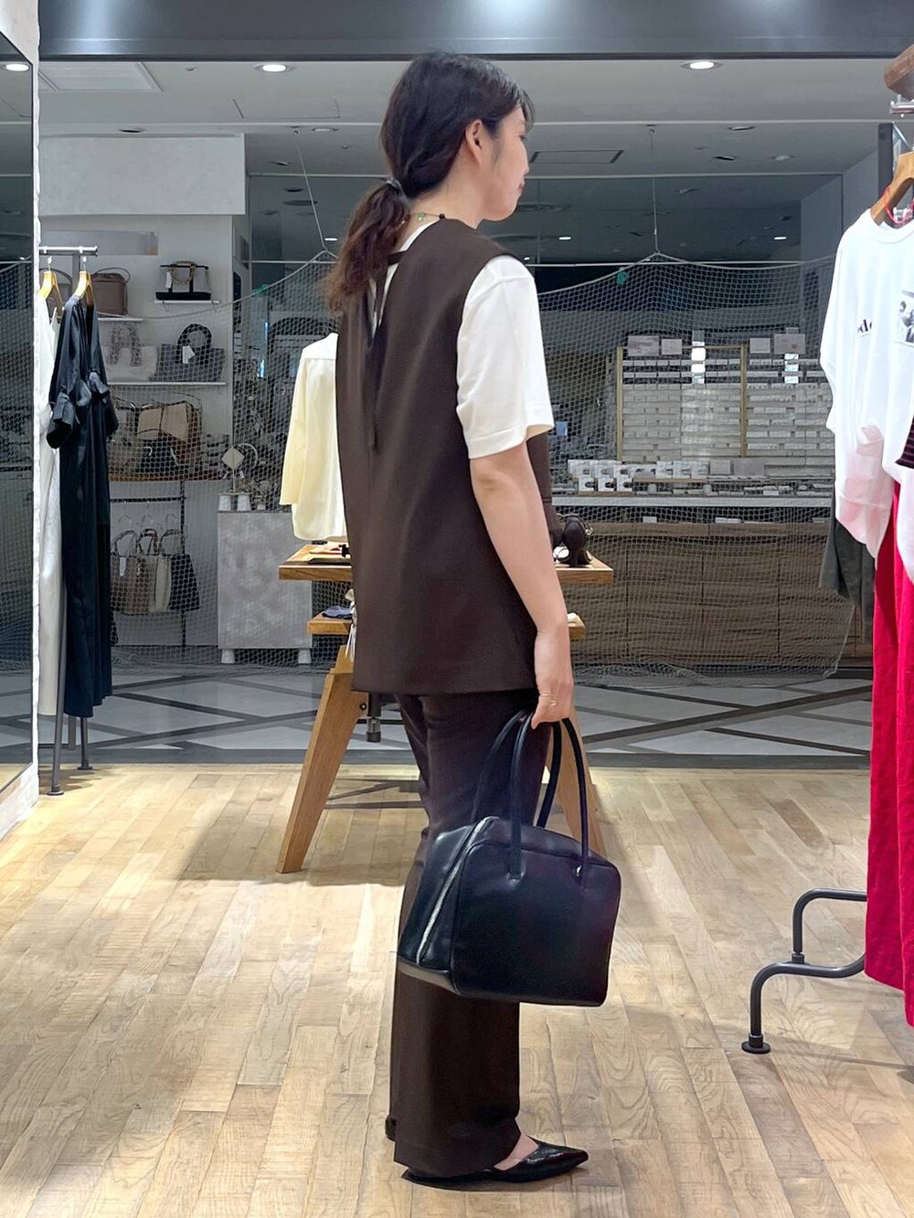 ブラック系のボストンバッグ、ホワイト系のTシャツ/カットソー、ブラウン系のパンツドレスを着用したレディースの秋コーディネートの2枚目の写真