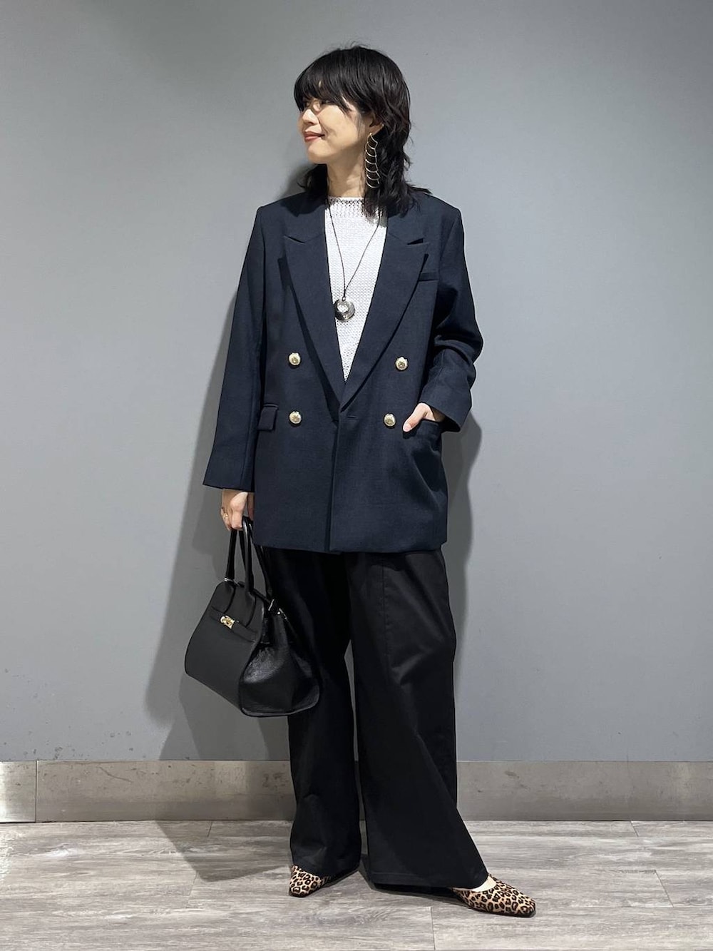 ブルー系のテーラードジャケット、ブラック系のショルダーバッグ、グレー系のニット/セーターを着用したレディースの春コーディネートの7枚目の写真