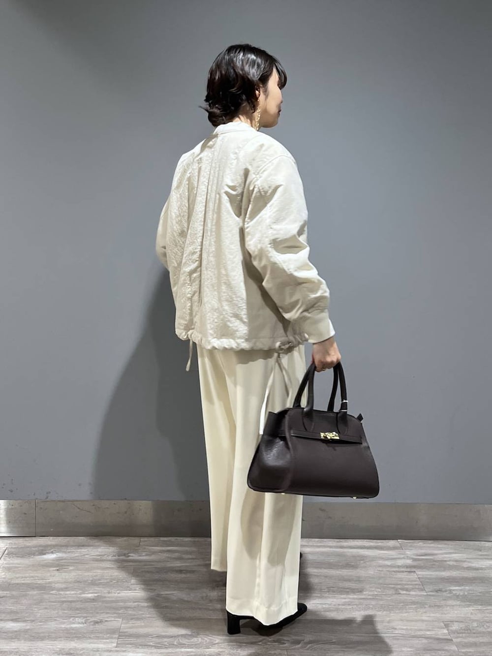 ホワイト系のスラックス、ベージュ系のMA-1、ブラック系のパンプスを着用したレディースの冬コーディネートの2枚目の写真