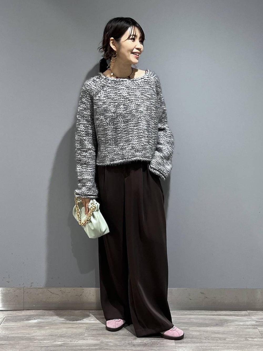 ブラウン系のスラックス、グリーン系のショルダーバッグ、グレー系のニット/セーターを着用したレディースの冬コーディネートの8枚目の写真