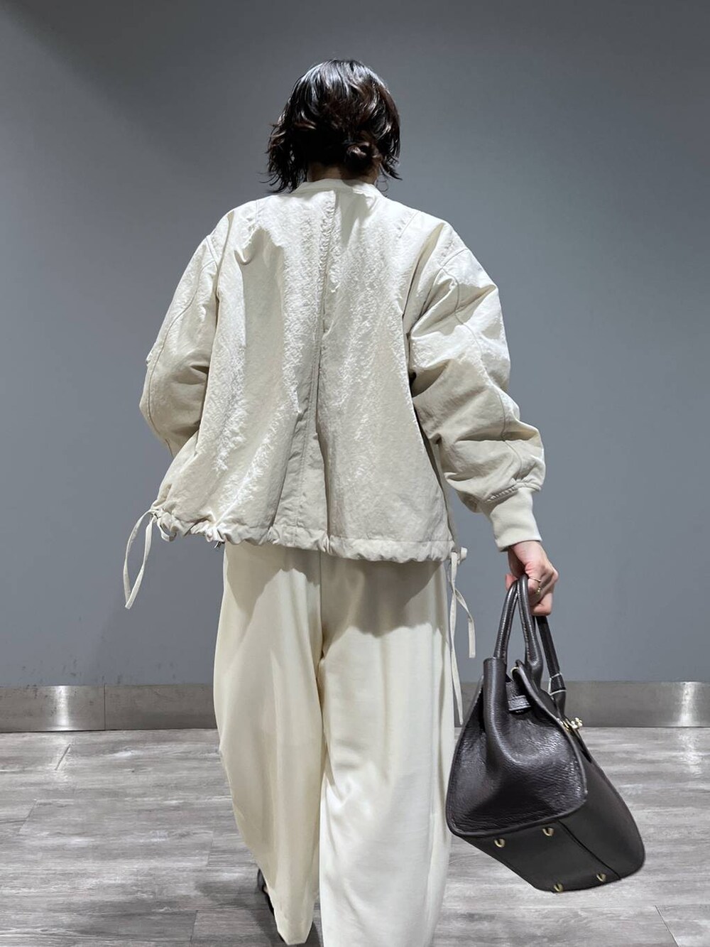 ホワイト系のスラックス、ベージュ系のMA-1、ブラック系のパンプスを着用したレディースの冬コーディネートの7枚目の写真