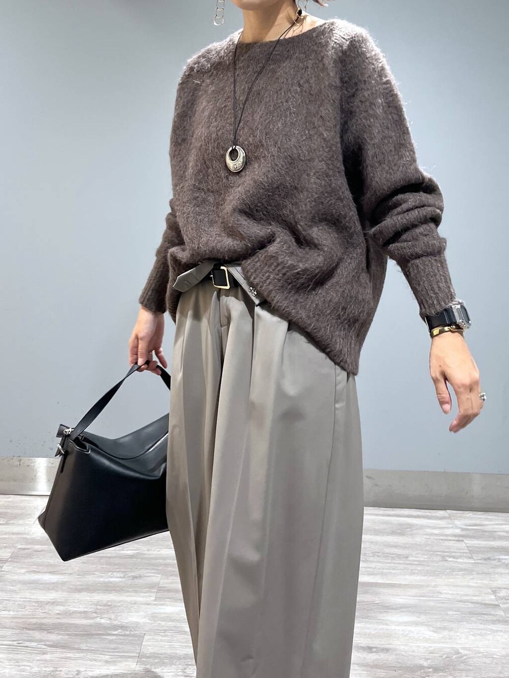 ブラウン系のニット/セーター、ブラック系のショルダーバッグ、ブラック系のブーツを着用したレディースの秋コーディネートの6枚目の写真