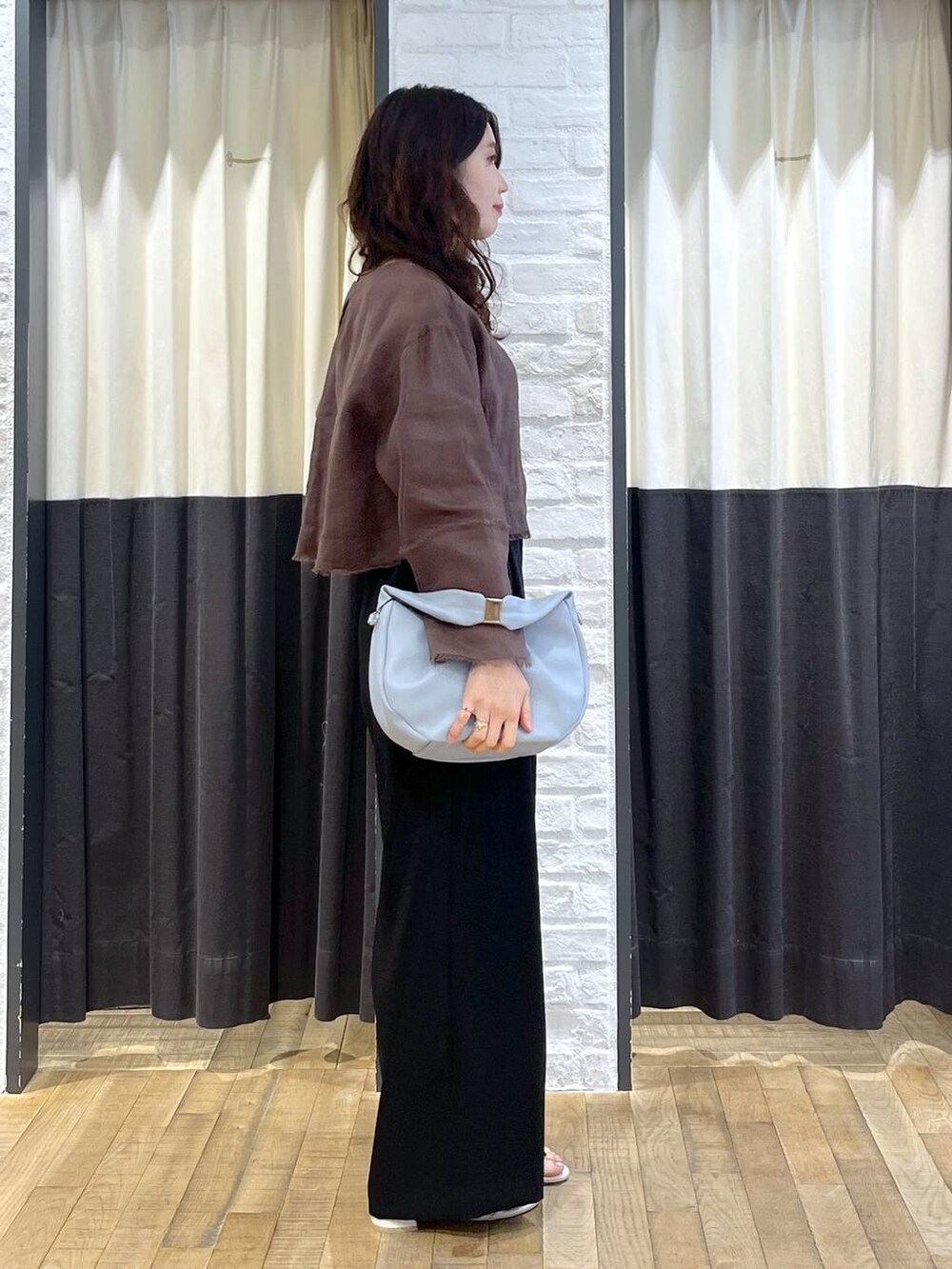 ブルー系のハンドバッグ、ブラウン系のシャツ/ブラウス、ホワイト系のサンダルを着用したレディースの秋コーディネートの2枚目の写真