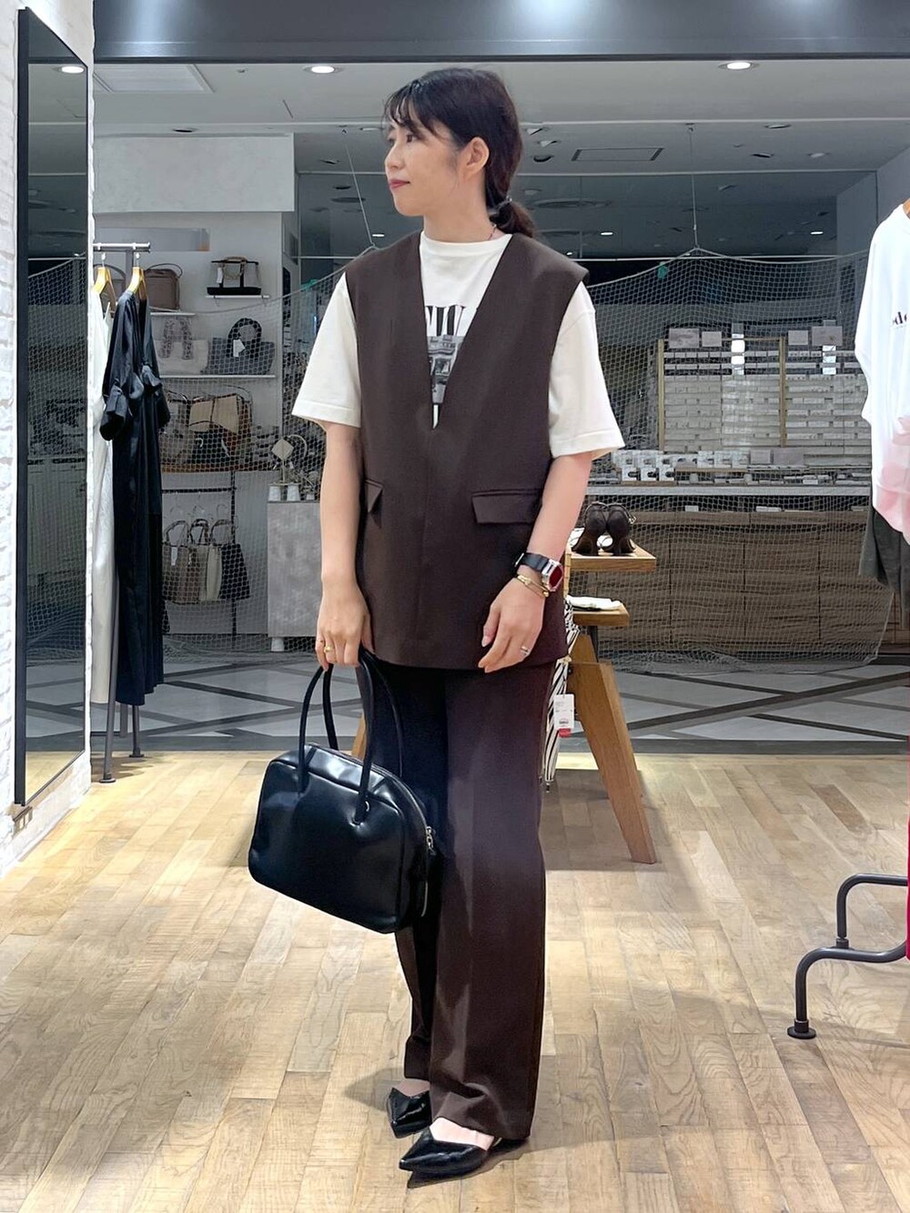 ブラック系のボストンバッグ、ホワイト系のTシャツ/カットソー、ブラウン系のパンツドレスを着用したレディースの秋コーディネートの6枚目の写真