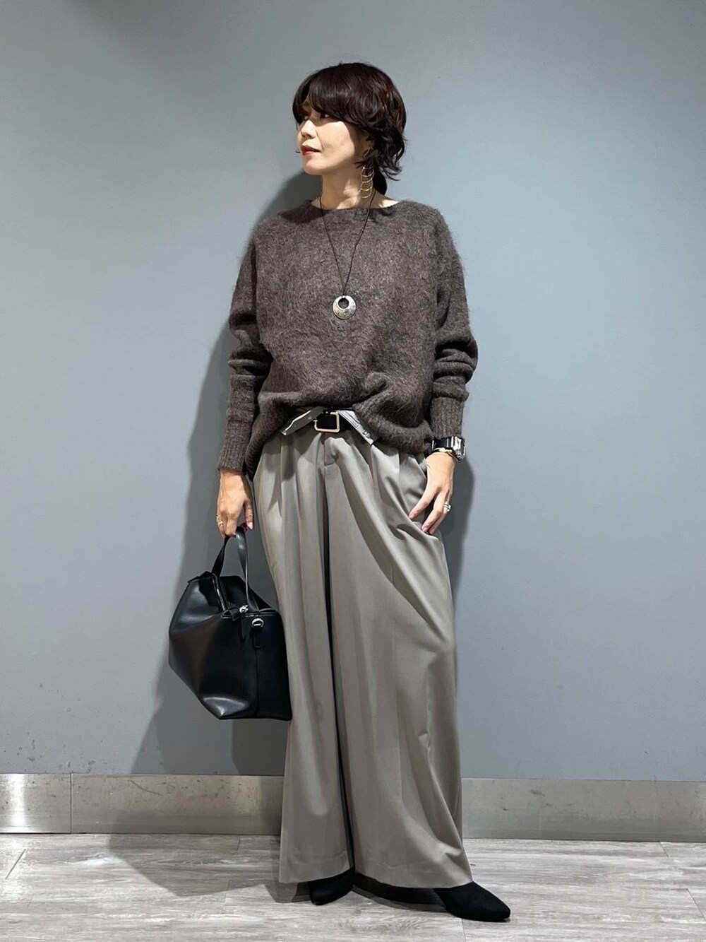 ブラウン系のニット/セーター、ブラック系のショルダーバッグ、ブラック系のブーツを着用したレディースの秋コーディネートの7枚目の写真