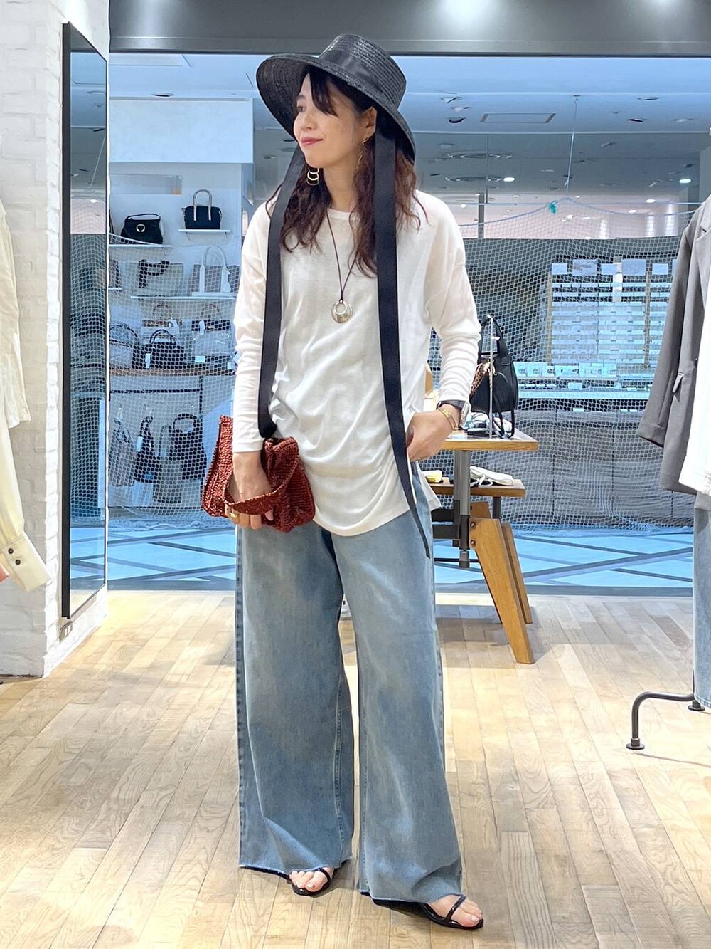 ブルー系のデニムパンツ、ブラック系のサンダル、ホワイト系のTシャツ/カットソーを着用したレディースの春コーディネートの4枚目の写真