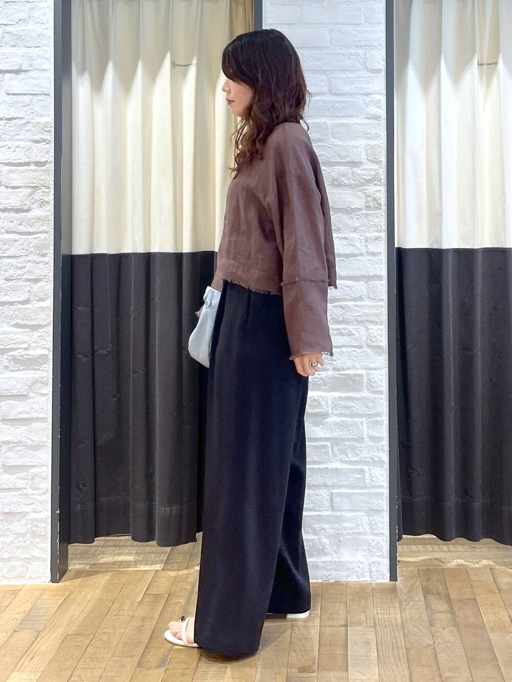 ブルー系のハンドバッグ、ブラウン系のシャツ/ブラウス、ホワイト系のサンダルを着用したレディースの秋コーディネートの4枚目の写真