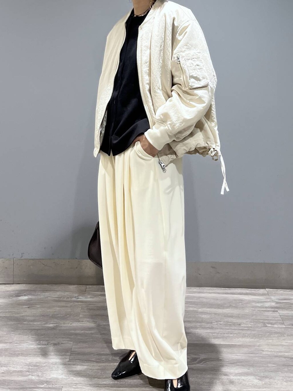 ホワイト系のスラックス、ベージュ系のMA-1、ブラック系のパンプスを着用したレディースの冬コーディネートの8枚目の写真