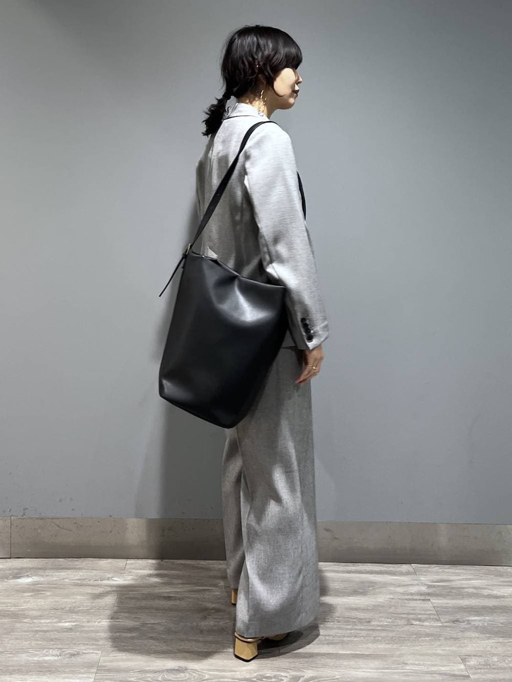 ブラック系のトートバッグ、ブラック系のノーカラージャケット、ブラック系のベストを着用したレディースの春コーディネートの2枚目の写真