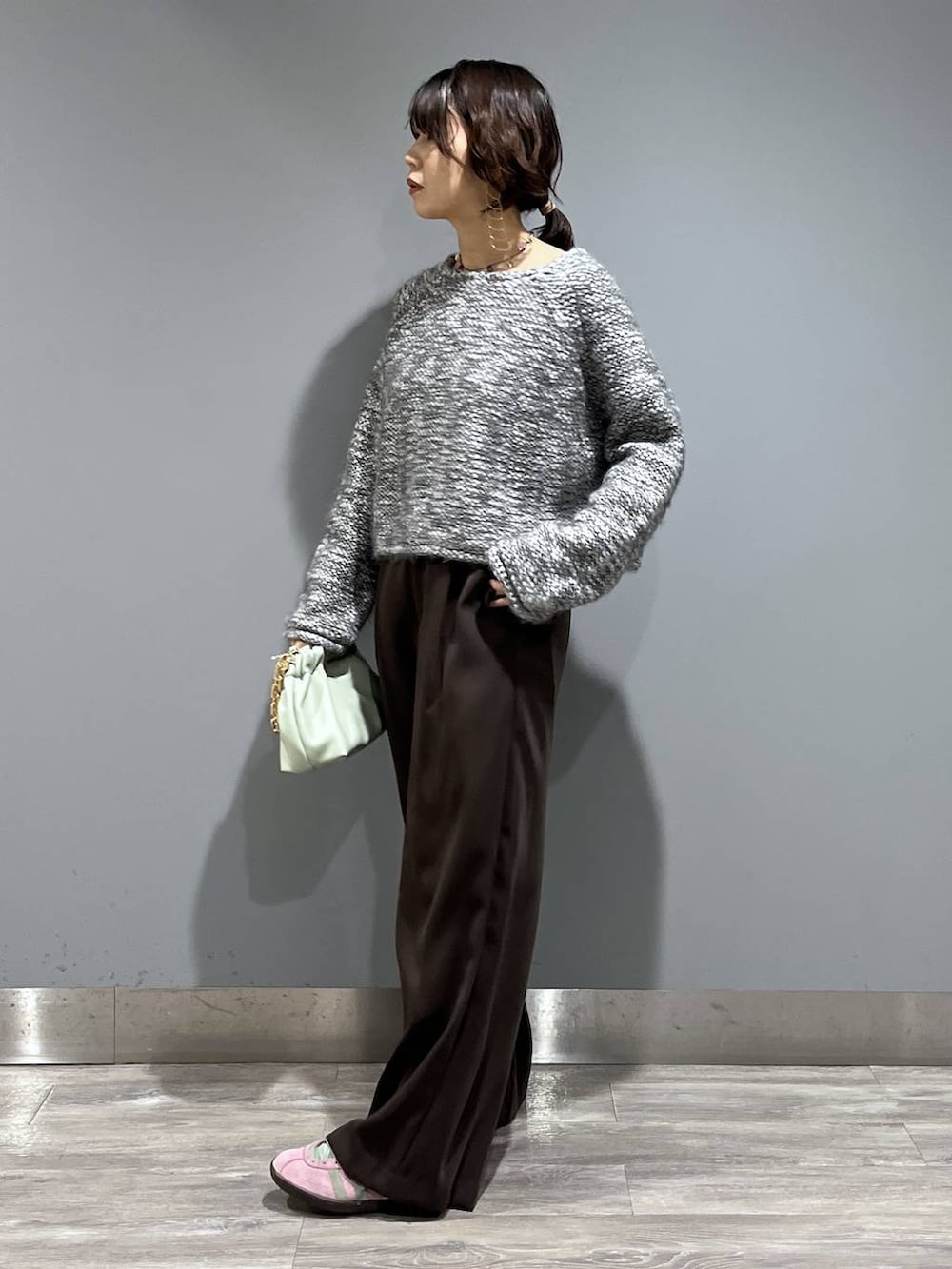 ブラウン系のスラックス、グリーン系のショルダーバッグ、グレー系のニット/セーターを着用したレディースの冬コーディネートの4枚目の写真