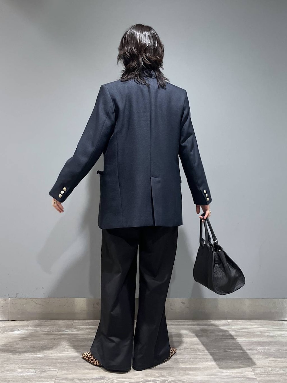 ブルー系のテーラードジャケット、ブラック系のショルダーバッグ、グレー系のニット/セーターを着用したレディースの春コーディネートの3枚目の写真