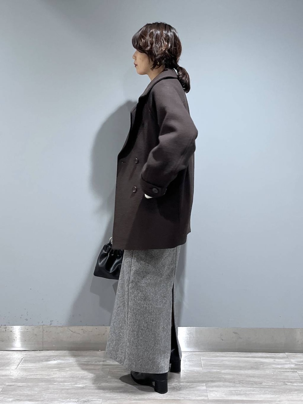 ブラウン系のピーコート、ホワイト系のカーディガン/ボレロ、ブラック系のブーツを着用したレディースの秋コーディネートの4枚目の写真