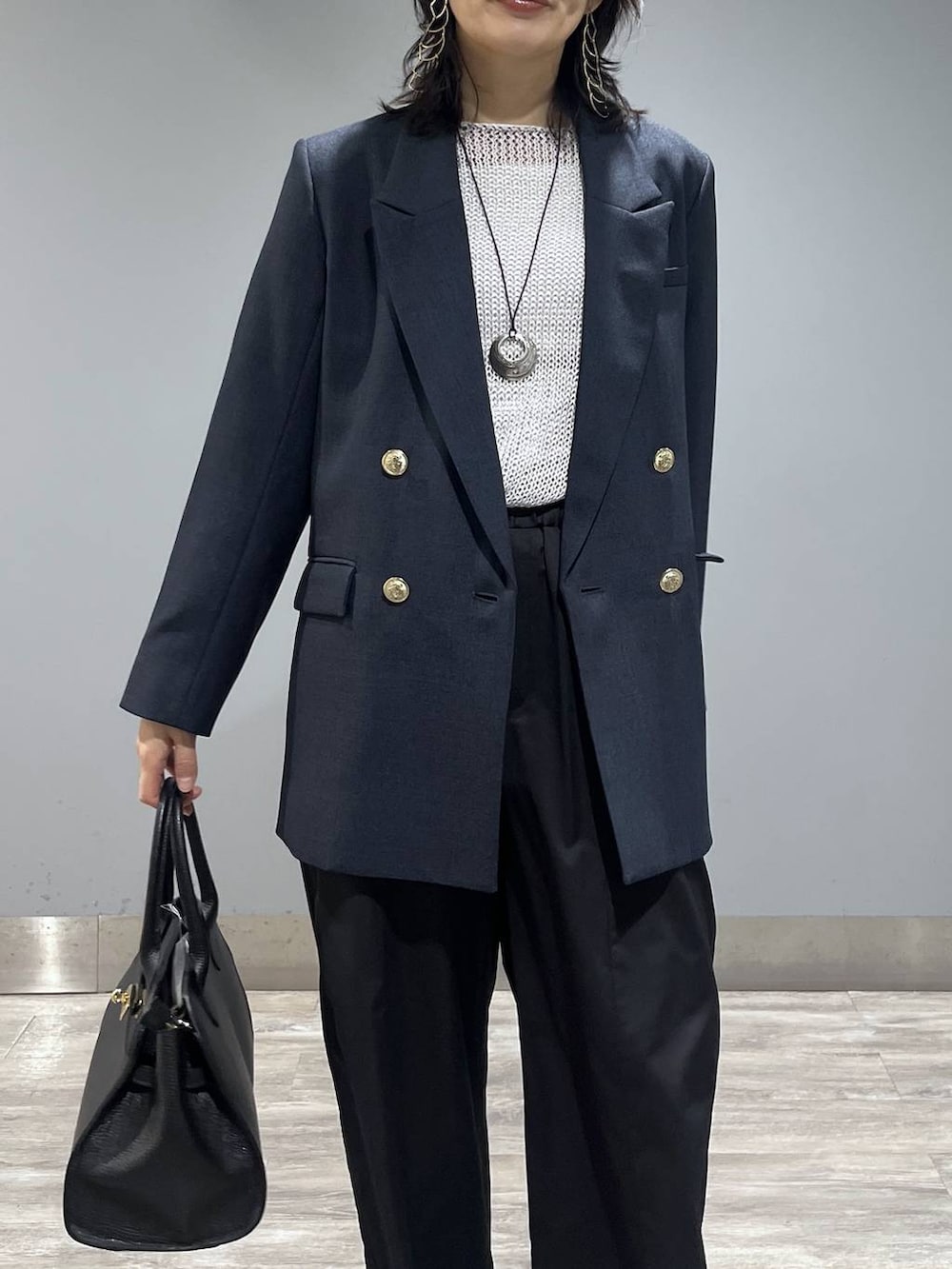 ブルー系のテーラードジャケット、ブラック系のショルダーバッグ、グレー系のニット/セーターを着用したレディースの春コーディネートの5枚目の写真