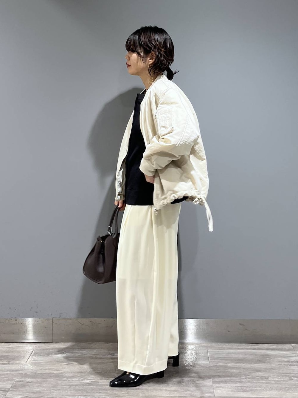 ホワイト系のスラックス、ベージュ系のMA-1、ブラック系のパンプスを着用したレディースの冬コーディネートの4枚目の写真