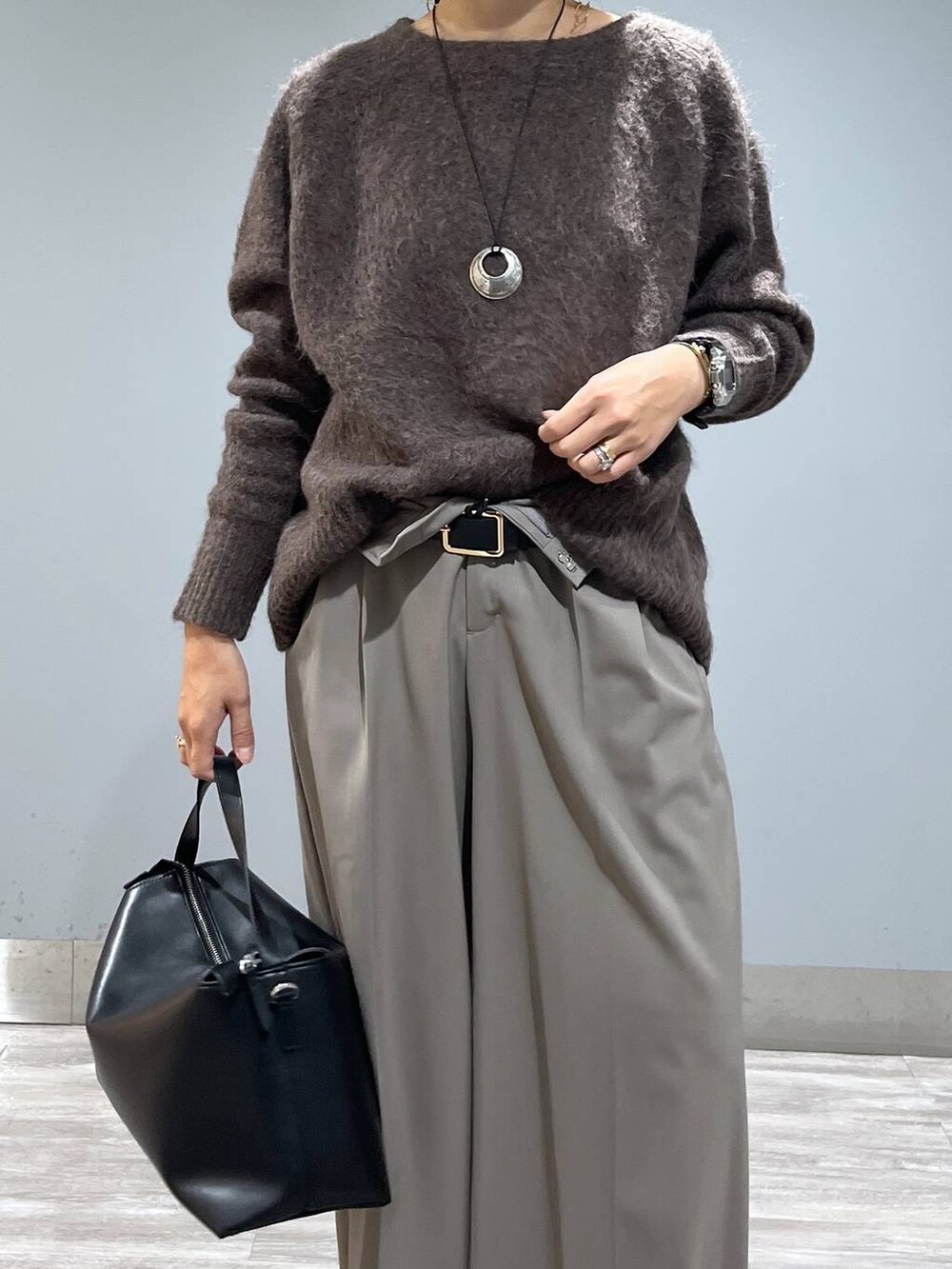 ブラウン系のニット/セーター、ブラック系のショルダーバッグ、ブラック系のブーツを着用したレディースの秋コーディネートの4枚目の写真