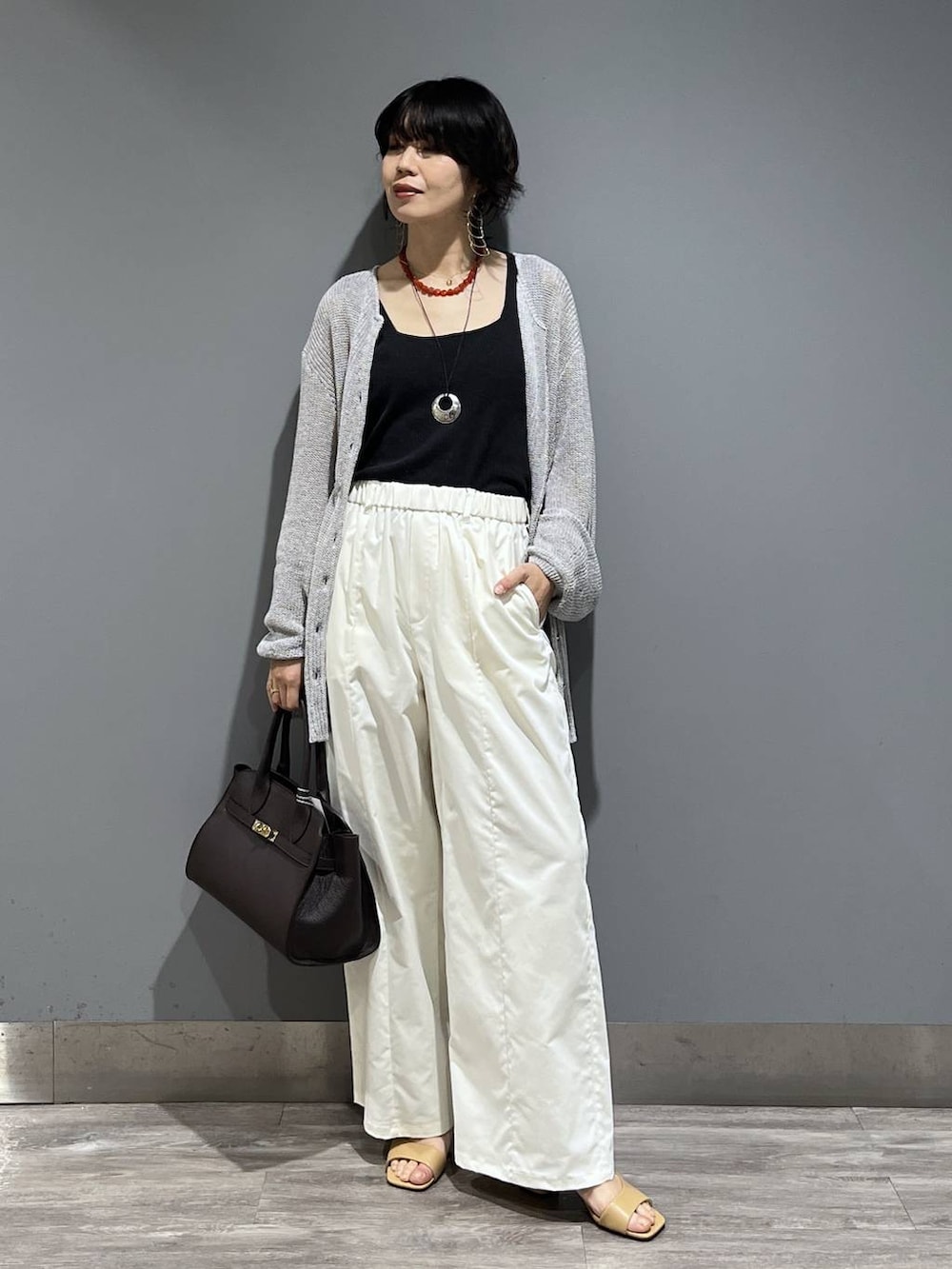 ブラウン系のショルダーバッグ、ホワイト系のスラックス、グレー系のカーディガン/ボレロを着用したレディースの春コーディネートの8枚目の写真
