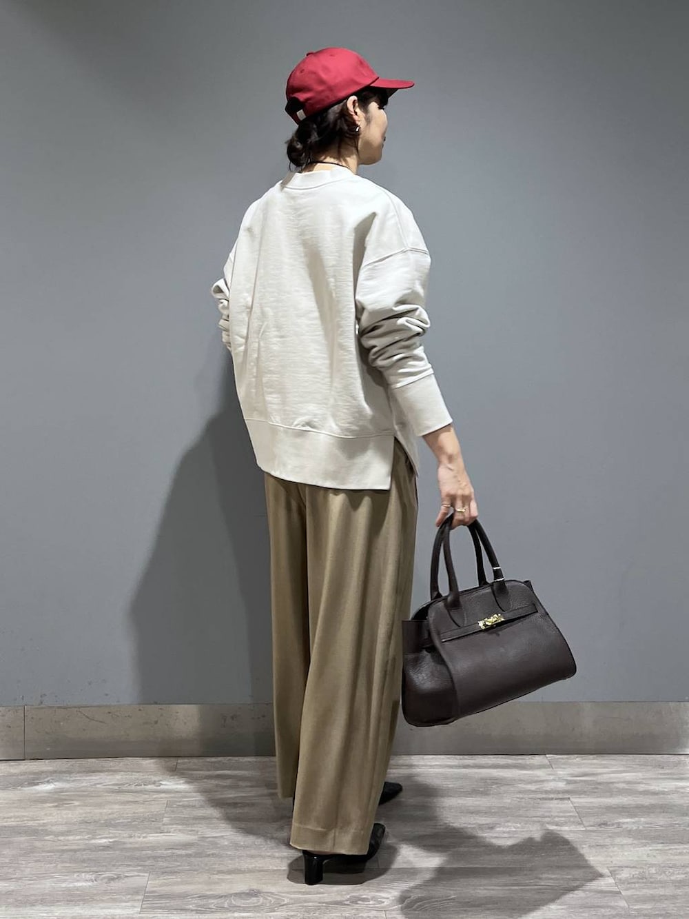 ベージュ系のスラックス、ブラック系のパンプス、ブラウン系のショルダーバッグを着用したレディースの冬コーディネートの2枚目の写真