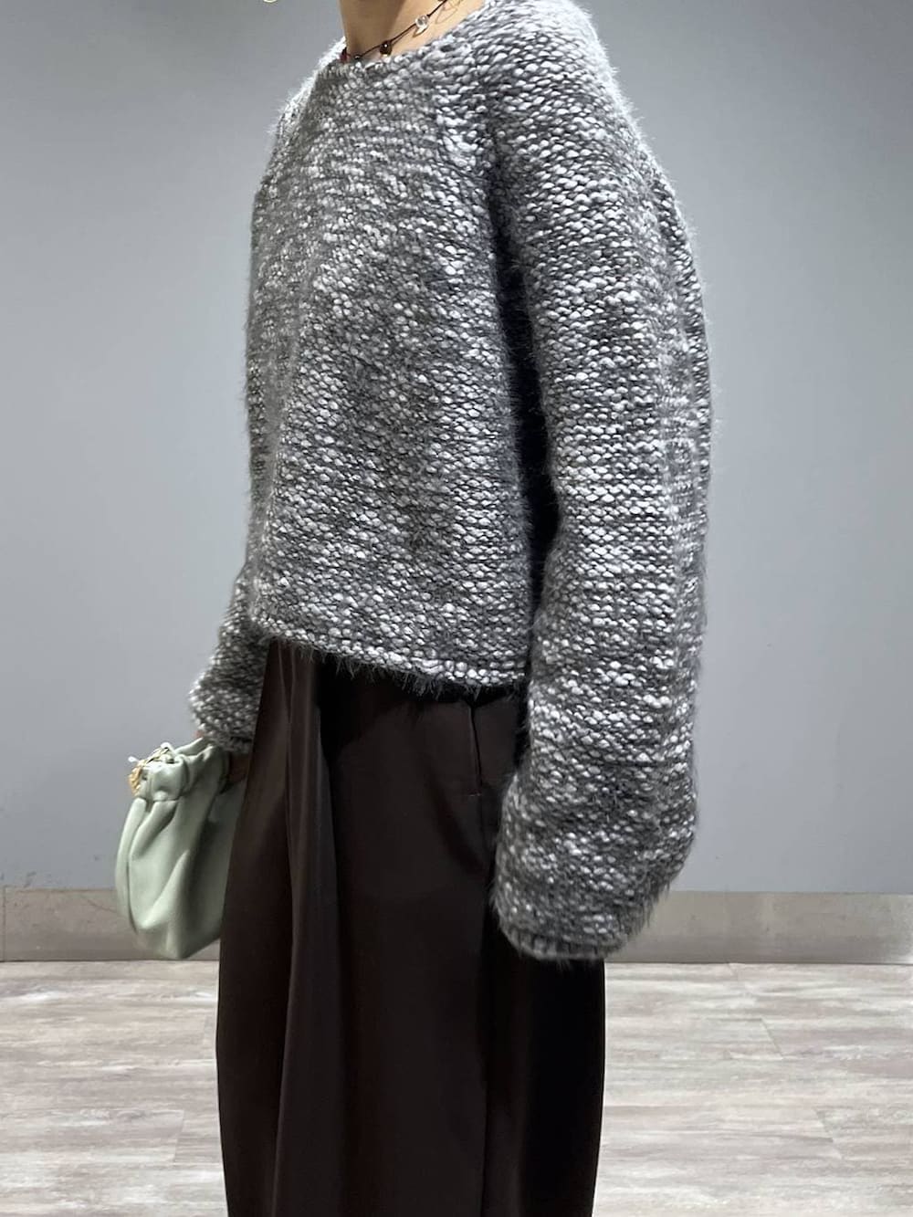 ブラウン系のスラックス、グリーン系のショルダーバッグ、グレー系のニット/セーターを着用したレディースの冬コーディネートの5枚目の写真