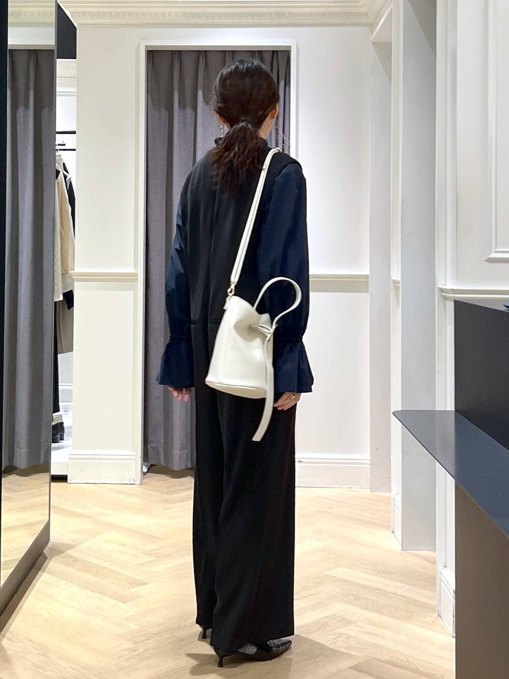 ホワイト系のショルダーバッグ、ブラック系のパンプス、ブラック系のサロペット/オーバーオールを着用したレディースの冬コーディネートの2枚目の写真