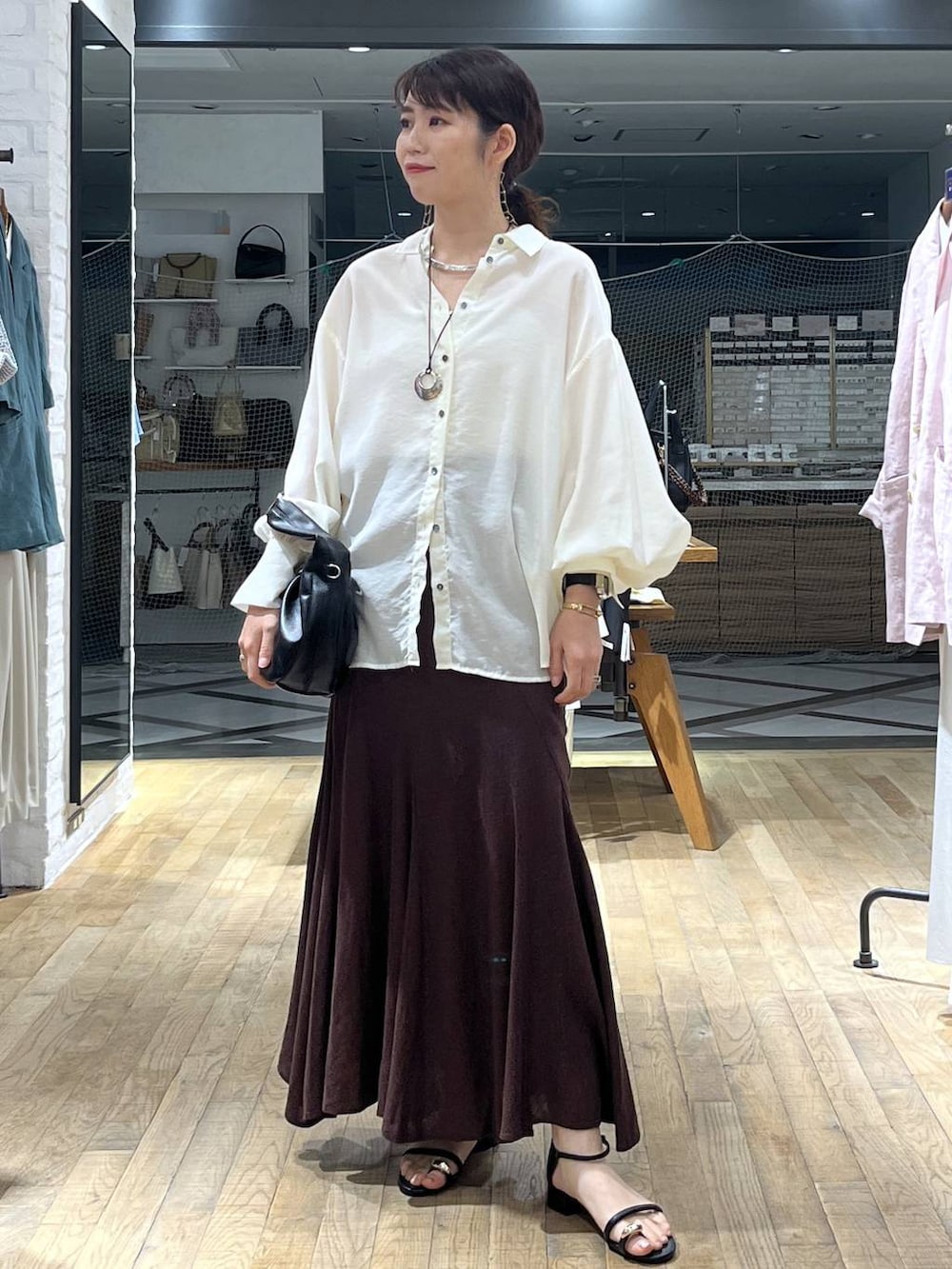 ホワイト系のシャツ/ブラウス、ブラック系のハンドバッグ、ブラック系のサンダルを着用したレディースの春コーディネートの5枚目の写真