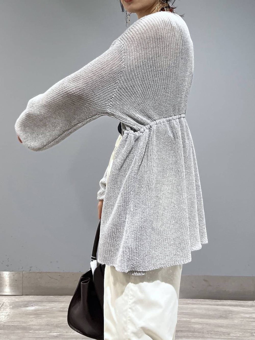 ブラウン系のショルダーバッグ、ホワイト系のスラックス、グレー系のカーディガン/ボレロを着用したレディースの春コーディネートの6枚目の写真