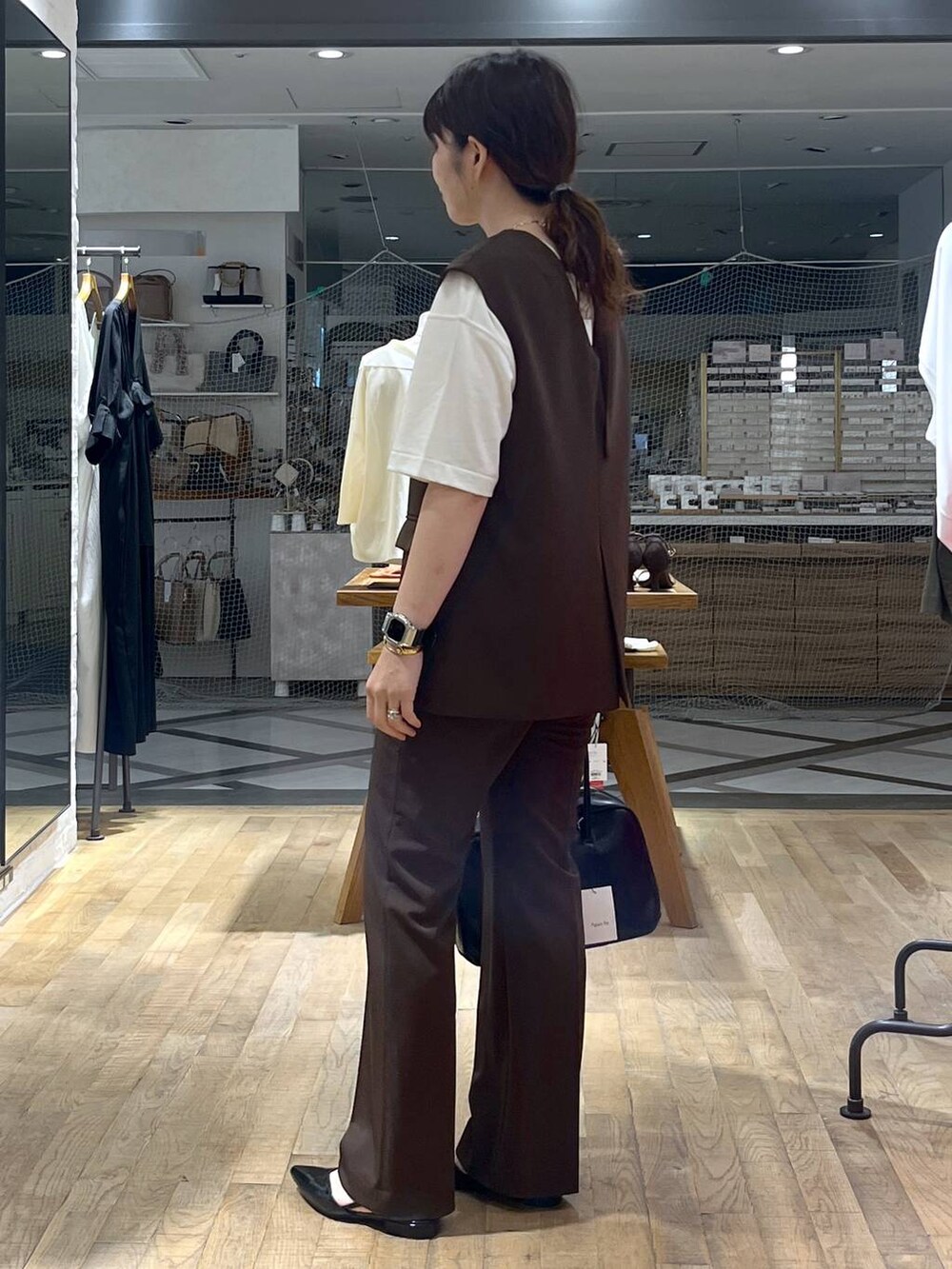 ブラック系のボストンバッグ、ホワイト系のTシャツ/カットソー、ブラウン系のパンツドレスを着用したレディースの秋コーディネートの4枚目の写真